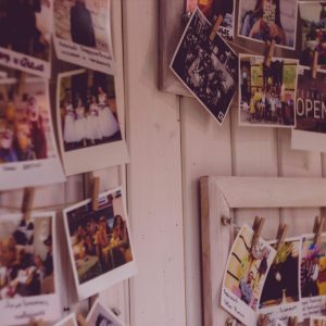 Collection Of Vintage Polaroid Photos Clipped To A Wooden Wall Indoors.