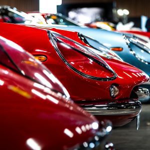 A Lineup Of Vintage Sports Cars Showcased Indoors, Featuring Vibrant Colors And Classic Designs.