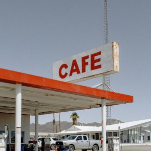 A Rustic Gas Station And Café Under Clear Skies, Blending Vintage Architecture With Desert Landscape.
