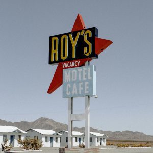 Iconic Roy's Motel Sign In A Deserted Landscape Under Clear Skies.