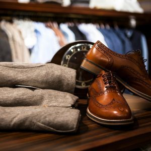 Stylish Leather Shoes Displayed With Gray Clothing In A Chic Boutique Setting.