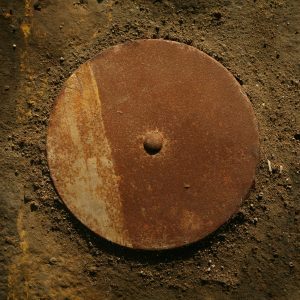 Detailed Close Up Of A Rusty Metal Disk On A Rough, Earthy Surface Conveying Texture And Decay.