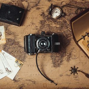 A Nostalgic Flat Lay Combining Vintage Travel Items, An Analog Camera, And A World Map.