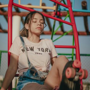 A Young Woman In Casual Wear Relaxes With Her Roller Skates At A Colorful Playground.