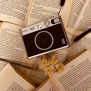 A Vintage Camera Placed On Open Books With Flowers, Creating A Classic Aesthetic.