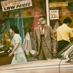 Retro Styled Shoppers Pass A Vintage Store In A Classic City Setting. Nostalgic Vibe.