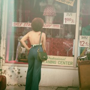 A Woman In Retro Fashion Standing Outside A Vintage Store With Sale Signs In NYC.