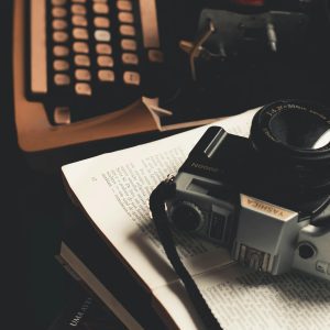 Retro Scene Featuring A Vintage Camera And Typewriter On An Open Book.