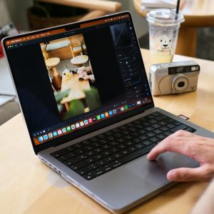 Person Edits Photo On Laptop In A Cozy Café, Capturing Creative Digital Work Vibe.