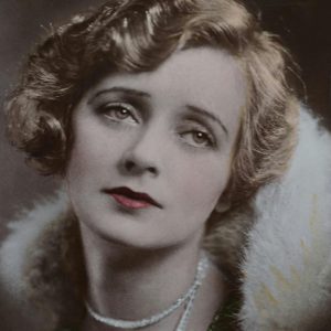 Classic Vintage Portrait Of A Woman Wearing A Fur Coat And Pearl Necklace With Red Lips.