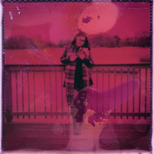 Artistic Pink Tinted Photo Of Person Standing By A Railing Outdoors.