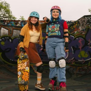 Two Young Adults Enjoying Skateboarding And Roller Skating At A Colorful Skatepark.