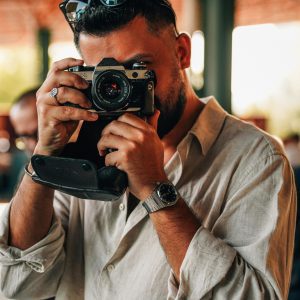 A Man Photographing With A Vintage Camera Indoors, Creating Warm And Artistic Vibes.