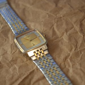 Close Up Of A Classic Vintage Wristwatch With A Metal Band Placed On Textured Brown Paper.