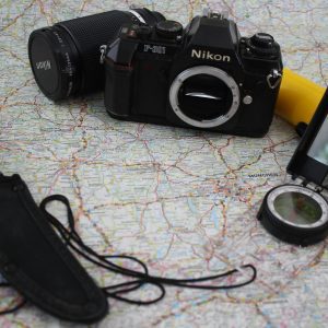 A Nostalgic Journey With A Nikon Camera, Compass, Knife, And Flashlight On A Detailed Map.