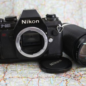 Classic Nikon F 301 Camera With Lens Displayed On World Map, Evokes Travel And Photography Nostalgia.