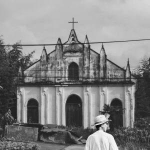Black And White Photo Of A Person Walking Toward An Old Church, Evoking Nostalgia.