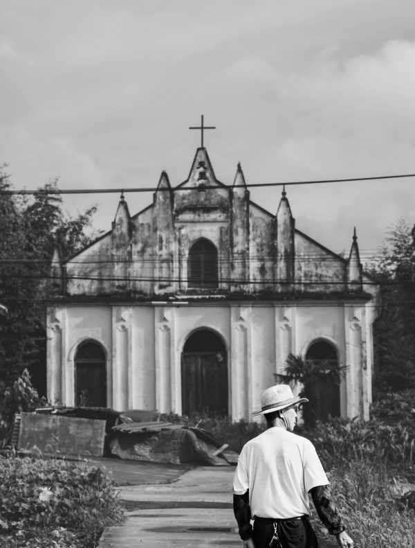 Black And White Photo Of A Person Walking Toward An Old Church, Evoking Nostalgia.