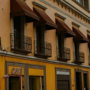 Yellow Building Facade With Balconies And A Café Sign, Elegant Urban Architecture.
