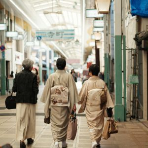 People In Kimonos Walking Through A Traditional Kyoto Indoor Market, Capturing Cultural Elegance.