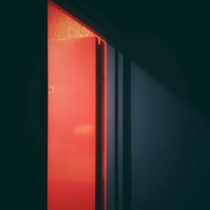 A Captivating Image Of An Open Door Illuminated By A Neon Red Light, Creating A Sense Of Mystery.