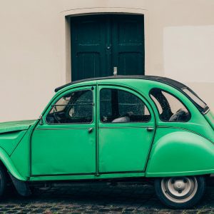 Classic Green Car Parked By An Old Building In Berlin, Showcasing Vintage Automotive Style.
