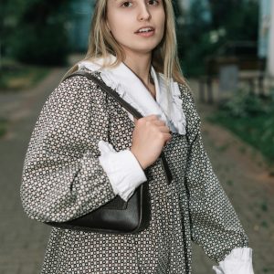 A Young Woman In A Vintage Dress Strolls Outdoors, Carrying A Handbag, Exuding A Classic Style.