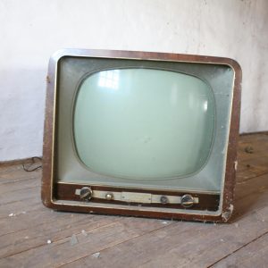 Vintage Wooden Television Sitting On A Dusty, Rustic Wooden Floor In An Abandoned Room.