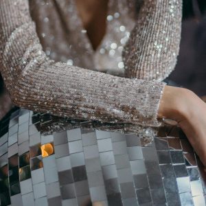 Elegant Woman In Sequin Dress Posing With A Large Disco Ball, Evoking A Glittering Party Vibe.