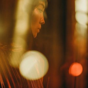 Portrait Of A Woman Highlighted By Soft Golden Lighting At A Festive, Indoor Event. Glamorous And Mysterious.