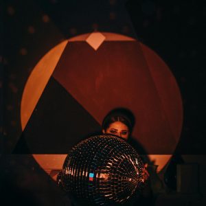 A Stylish Woman Holding A Disco Ball, Capturing The Vibrant Nightlife Atmosphere.