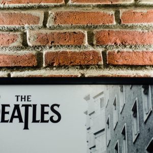 A Vintage Beatles Poster Against A Classic Brick Wall Background, Emphasizing Retro Style.