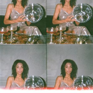 A Glamorous Woman In A Stylish Dress Posing With A Disco Ball Indoors, Capturing A Chic And Fashionable Vibe.