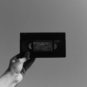 Artistic Shot Of A Vintage Cassette Held Against A Clear Sky In Monochrome.