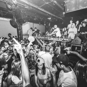Vibrant Nightclub Scene With DJ And Dancing Crowd Enjoying Live Music.