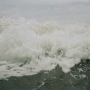 Capturing Dynamic Ocean Waves Crashing, Creating White Foam On A Cloudy Day.