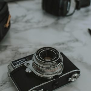 An Antique Camera And Headphones On A White Marble Surface, Perfect For Retro Tech Themes.