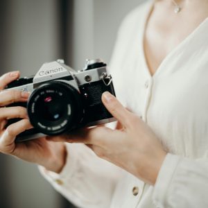 Close Up Of A Woman Holding A Vintage Canon Film Camera, Emphasizing Timeless Photography.