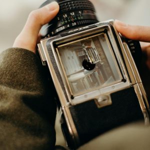 A Close Up Shot Of Hands Holding A Vintage Camera, Focusing On The Viewfinder.
