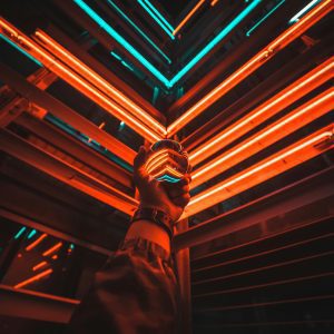A Hand Holding A Glowing Glass Ball Reflecting Vibrant Neon Lights In An Urban Setting At Night.