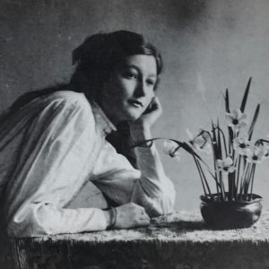 Classic Black And White Portrait Of A Woman Leaning On Table With Daffodils.