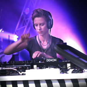 A Female DJ Engaged In Live Performance With Vibrant Lights In A Nightclub Setting.