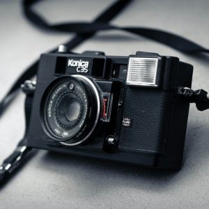 Classic Konica C35 Film Camera With A Strap, Showcasing Retro Design And Antique Charm.
