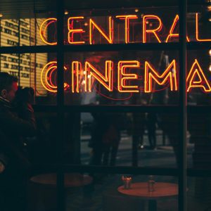 A Photographer Captures The Vibrant Neon Glow Of A Cinema Sign During The Evening.