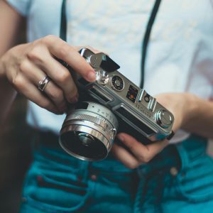 Young Woman Holding A Vintage Camera Outdoors, Showcasing Retro Photography Equipment.