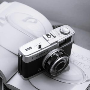 A Classic Olympus Trip 35 Camera Resting On An Open Book, Showcasing Retro Photography Charm.