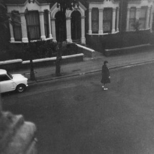 Monochrome Photo Of A Woman Walking On A London Street In The 1960s.