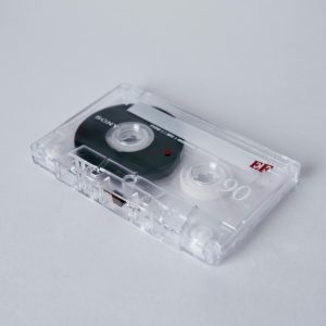 Close Up Of A Vintage Cassette Tape With Clear Casing On A White Background, Highlighting Audio Nostalgia.
