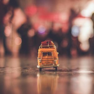 A Nostalgic Yellow Toy Van With Luggage, Reflecting On A City Street During Sunset.