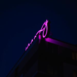 A Neon Pink Sign Adorns A Building In Berlin At Night, Offering A Striking Visual Contrast.